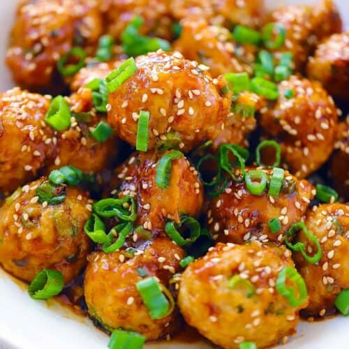 Square photo of Asian chicken meatballs with green onions and sesame seeds.