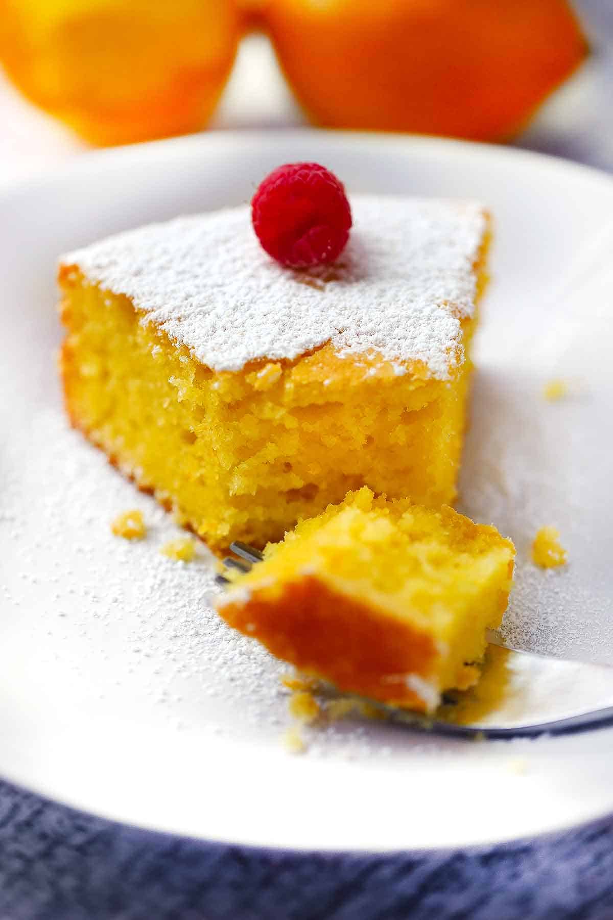 A fork cutting a piece out of a slice of lemon olive oil cake.