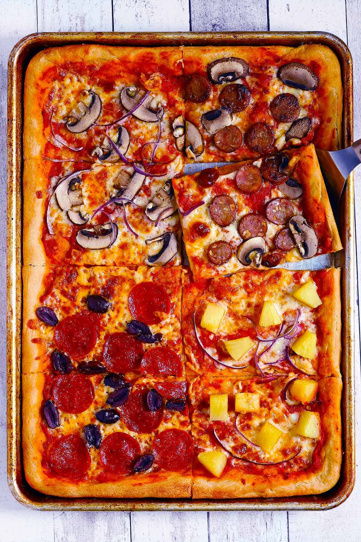 Overhead photo of a sheet pan pizza with a slice being taken out.