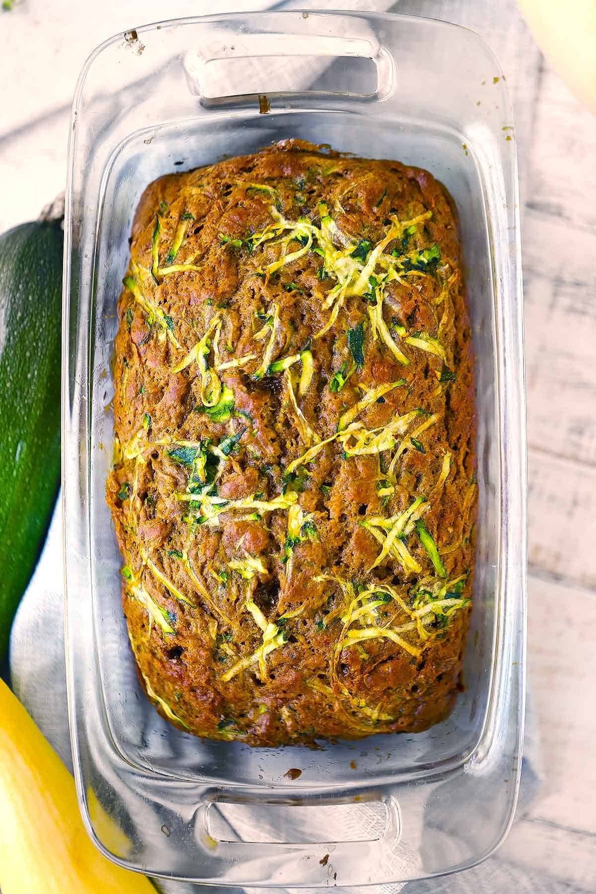 A loaf of olive oil zucchini bread in a loaf pan.