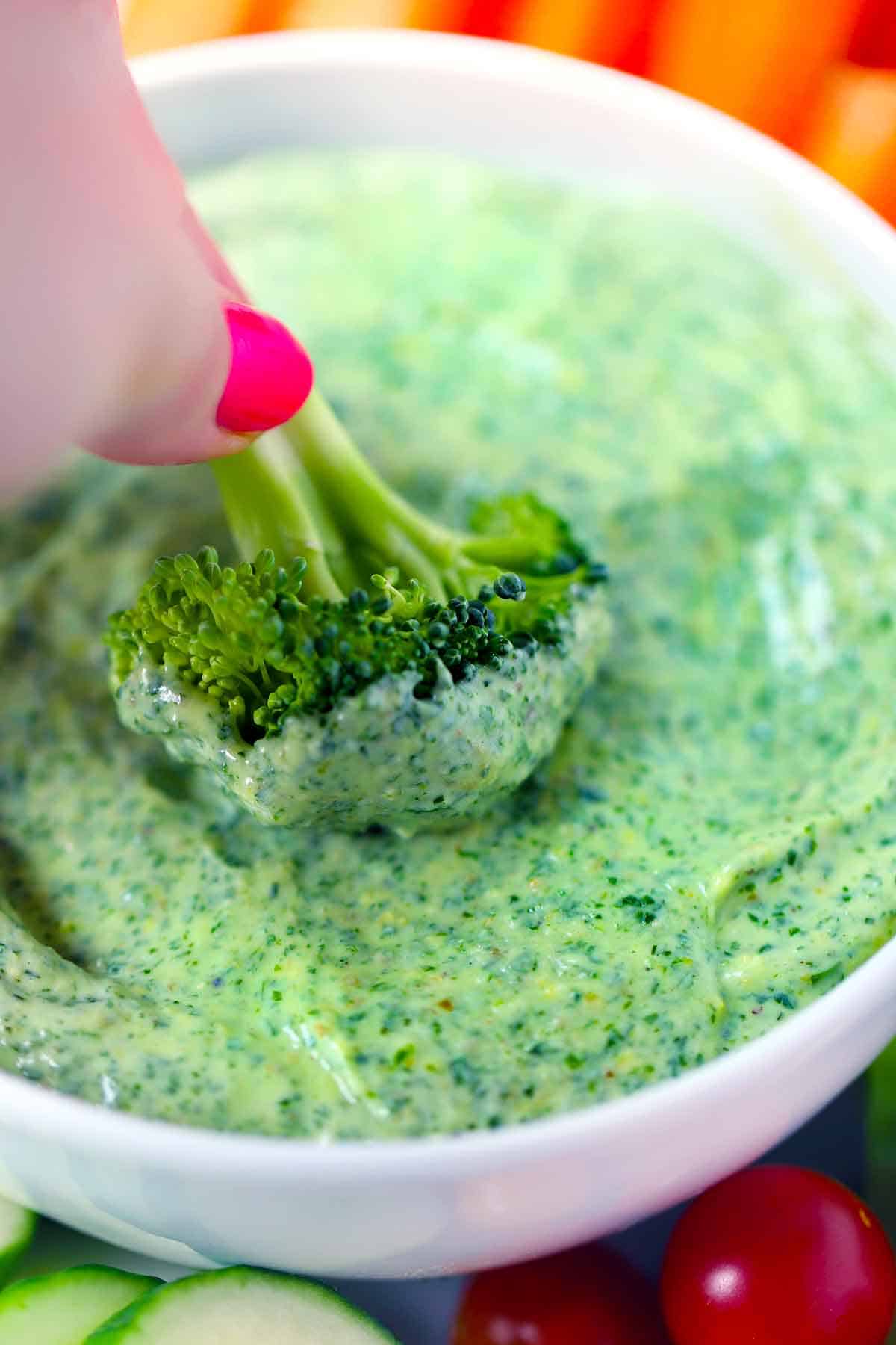 Dipping broccoli into Green Goddess Dressing.