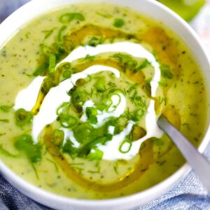 Square photo of zucchini soup in a bowl.
