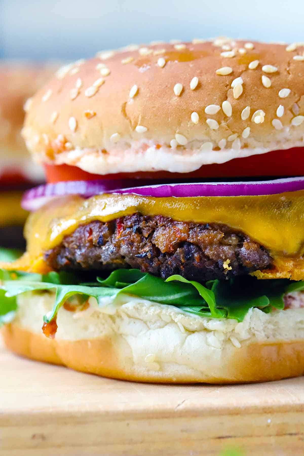 Close up side view of a black bean burger with cheese.