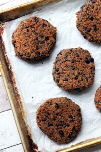 Black bean burgers on a parchment paper covered rimmed baking sheet.