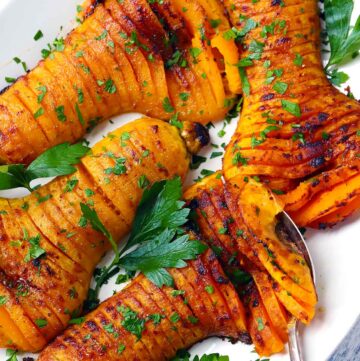 Square photo of hasselback butternut squash on a serving platter.