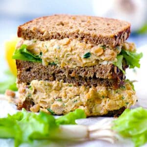 Square photo of a side view of a chickpea salad sandwich cut in half, resembling tuna salad in texture.
