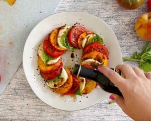 Drizzling a peach caprese salad with balsamic vinegar.
