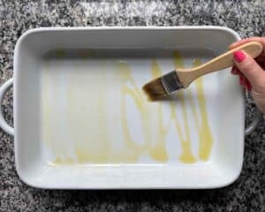 Greasing a baking dish by brushing it with olive oil.