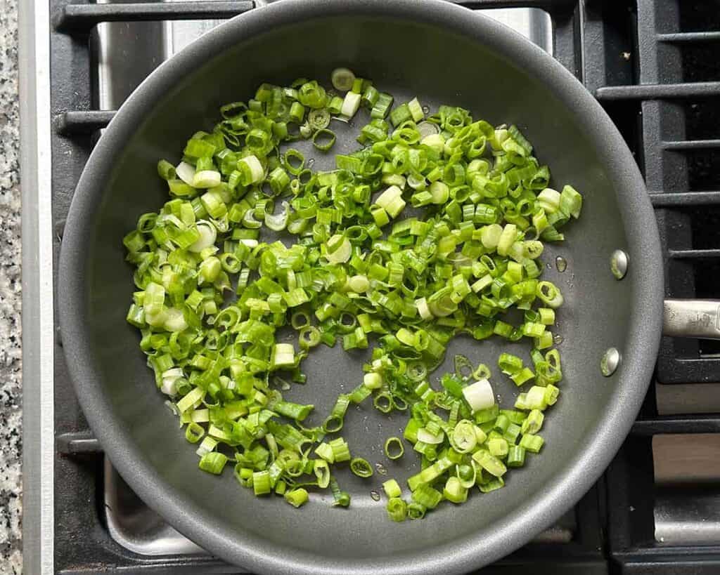 Sautéing green onions in olive oil in a nonstick skillet.