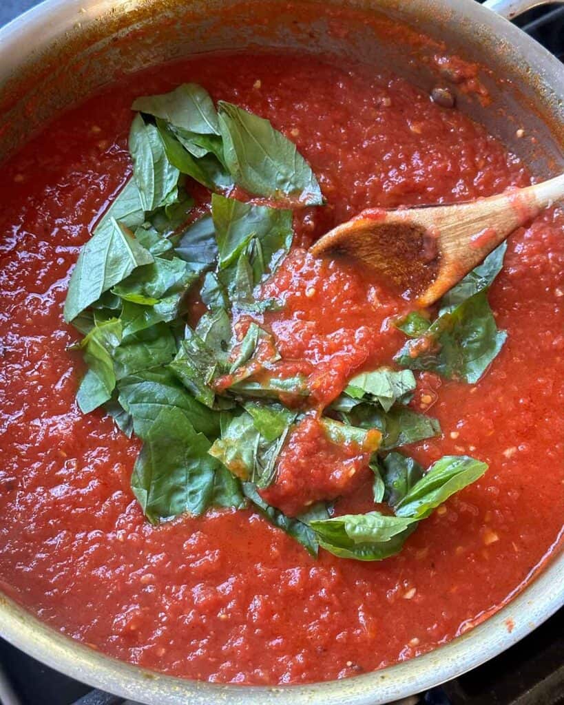 Stirring in fresh basil to a tomato sauce.