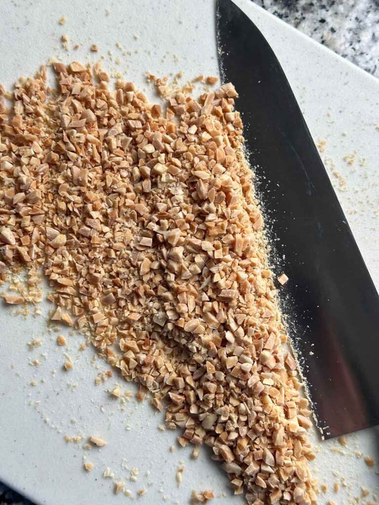 Chopped toasted slivered almonds on a cutting board showing how finely they should be chopped.