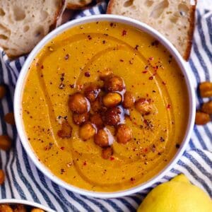 Square photo of overhead view of a bowl of chickpea soup drizzled with olive oil and topped with roasted chickpeas.