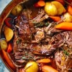 Square photo of Dutch Oven Pot Roast with Carrots and potatoes, garnished with thyme sprigs.